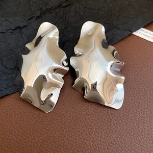 Close-up of elegant geometric crumpled silver stud earrings on a textured background