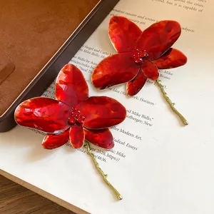 Dettaglio di eleganti orecchini a fiore in olio rosso con strass scintillanti