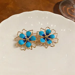 Eleganti orecchini a fiore in smalto blu con un raffinato design a contorno cavo dorato