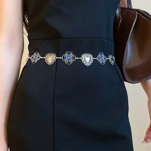 Detail shot of a vintage silver waist chain with blue gems and engraved heart links