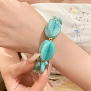 Detailed close-up of blue marbled acrylic beads on a chunky bracelet with gold accents