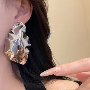 Detailed macro view of a large silver wrinkled geometric metal earring on model's ear
