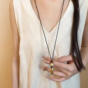 Dettaglio di un ciondolo a forma di pesce vintage su una collana di cuoio nero indossata