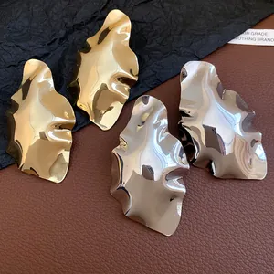 Detailed view of irregular geometric crumpled metallic stud earrings in gold and silver