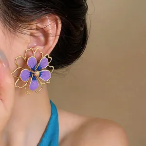 Primo piano di orecchini a fiore in smalto viola e blu con bordo traforato dorato