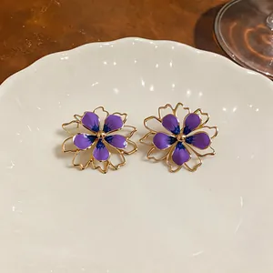 Dettaglio di eleganti orecchini a lobo a fiore viola con design a petali traforati.