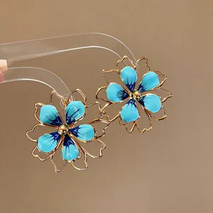 Primo piano dettagliato di orecchini a lobo a fiore in smalto blu e oro