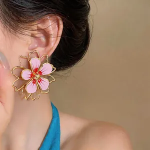 Dettaglio macro di eleganti orecchini a lobo a fiore in smalto rosa per gioielli moda