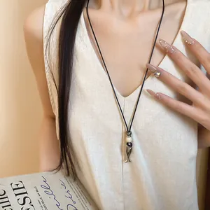 Dettaglio della collana con pendente a forma di pesce in ceramica su cordino in cuoio.