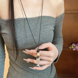 Vista dettagliata di una collana con ciondolo a forma di pesce in ceramica su cordino in cuoio