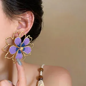 Dettaglio ravvicinato di uno squisito orecchino a fiore viola traforato su modella
