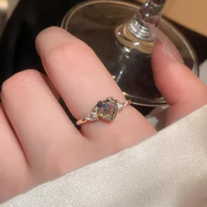Close-up of a heart-shaped iridescent zircon ring with a vintage gold-tone band.