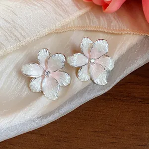 Detail-Makroaufnahme von rosa Blumenohrringen mit Zirkonia auf Seidenstoff