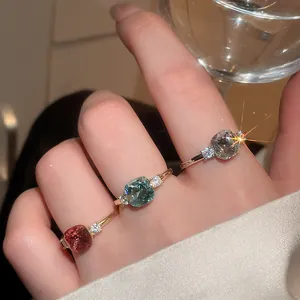 Close-up view of cushion-cut colorful zircon rings in red, teal, and grey finishes.
