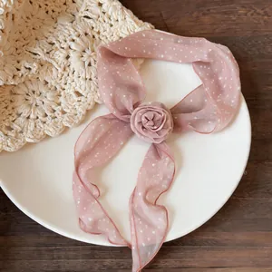 Detailed view of pink chiffon scarf featuring polka dots and central fabric rose flower