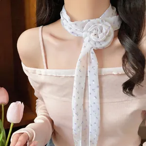 Close-up of white floral long scarf with fabric rose detail worn as a neck tie