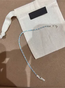 Detail view of a silver-tone tennis bracelet with blue and clear zircons on a pouch
