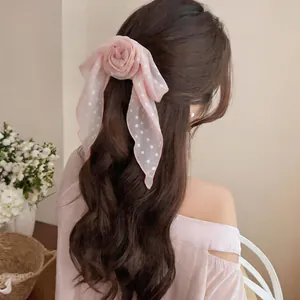 Detail view of pink polka dot ribbon with floral scrunchie styled in long wavy hair.