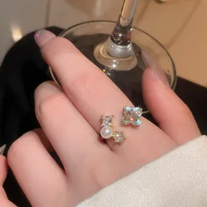 Close-up of vintage style gold-toned open ring with sparkling zircons and pearl.