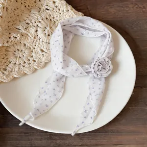 Detail of light purple skinny scarf with floral polka dots and fabric flower.