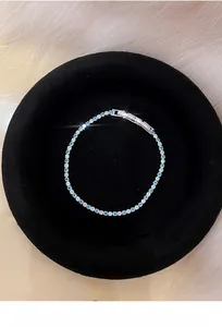 Macro view of a silver bracelet with alternating blue and white zircons on black velvet.