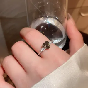 Close-up view of a silver ring featuring a brown heart-shaped zircon and white side stones
