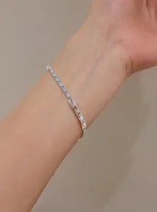 Detailed close-up of a delicate silver-toned zircon bracelet with blue and clear stones