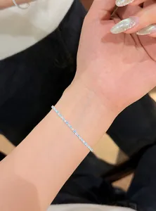 Close-up of a slim zircon bracelet with blue and white stones on a woman's wrist.