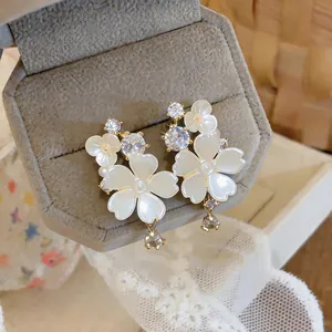 Close-up of elegant floral stud earrings with sparkling zircon and pearl-like petals