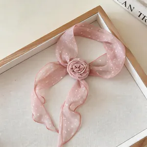 Close-up detail of a sweet pink polka dot silk scarf with a decorative 3D flower