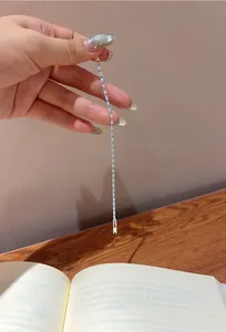 Vertical view of a delicate silver bracelet with blue and white zircons held by a hand.