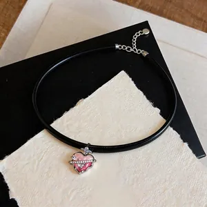 Detailed close-up of a pink enamel heart pendant with sparkling zircons on a black cord choker.