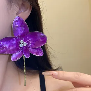 Vista dettagliata di un elegante orecchino a fiore in smalto viola con strass centrali