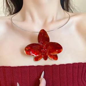 Dettaglio di una collana vintage con ciondolo a orchidea rossa e strass