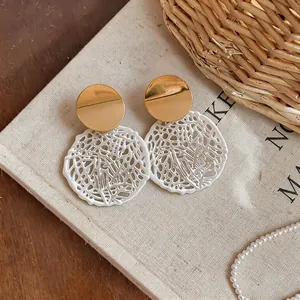 Detailed macro view of elegant round hollow lace earrings with gold studs on linen
