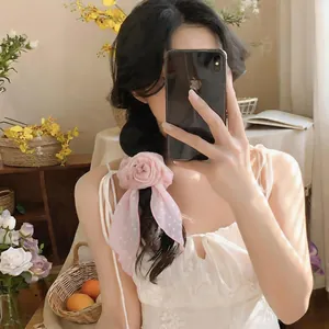 Close-up of a pink polka dot flower silk scarf worn as an elegant hair ribbon.