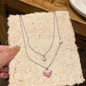 Close-up of elegant double-layer necklace with pink enamel heart and star pendants