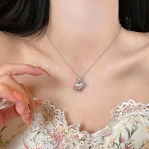 Detailed close-up of a sweet silver heart necklace with zircon planet ring on a model