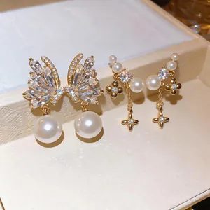 Detailed macro view of gold-plated zircon butterfly and pearl earrings.