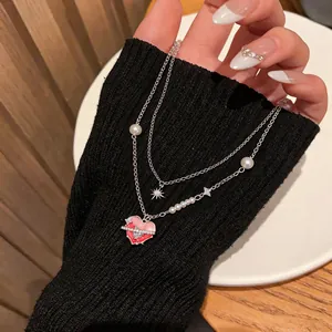 Detail of a double-layer necklace with pink enamel heart and zirconia star charms.