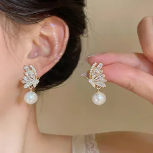 Detail view showing elegant zircon butterfly wings and a white pearl drop in gold finish.