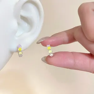 Detailansicht der bunten Tropföl-Smiley-Creolen, die am Ohr eines Models getragen werden