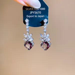 Detail showing sparkling purple zircon drop earrings on silver tag