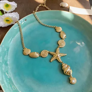 Macro detail view of an elegant gold sea shell and starfish charm necklace with pearl