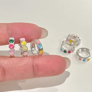 Makroaufnahme hochwertiger silberner Creolen mit bunten Emaille-Smileys und Herzmustern.