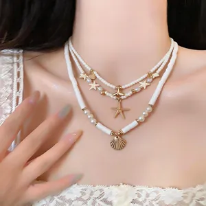 Detailed view of ocean-themed layered necklace with starfish and shell charms on model