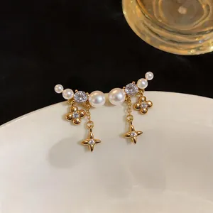 Close-up of elegant gold plated earrings with pearls, zircons and star-shaped charms