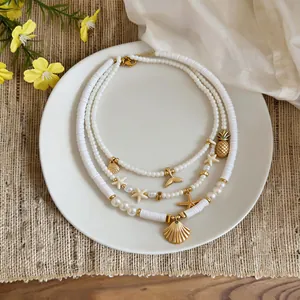Detail of multi-layered white bead necklace with gold starfish and shell charms.