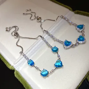 Détail de bracelets élégants en argent avec zircons bleus en forme de cœur dans un bel écrin