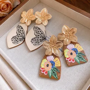 Vintage metal flower drop earrings with printed acetate pendants in a jewelry tray